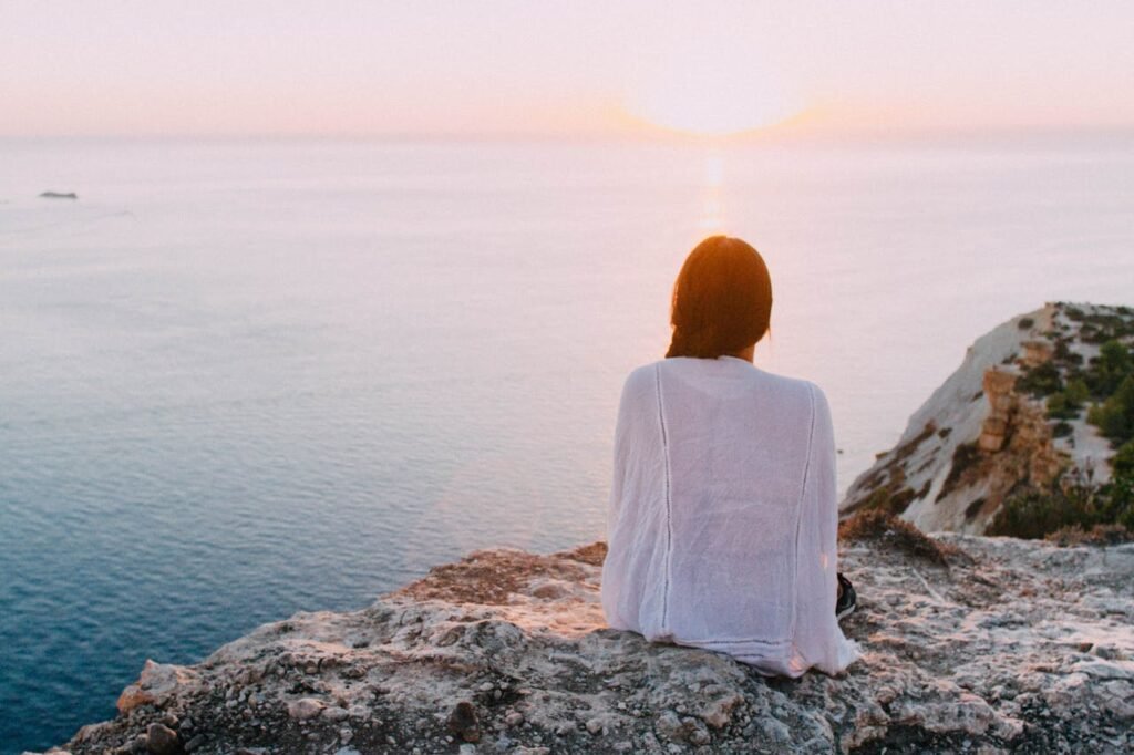 Saúde mental, mulher cudando da saúde mental ao contemplar o mar e meditar.